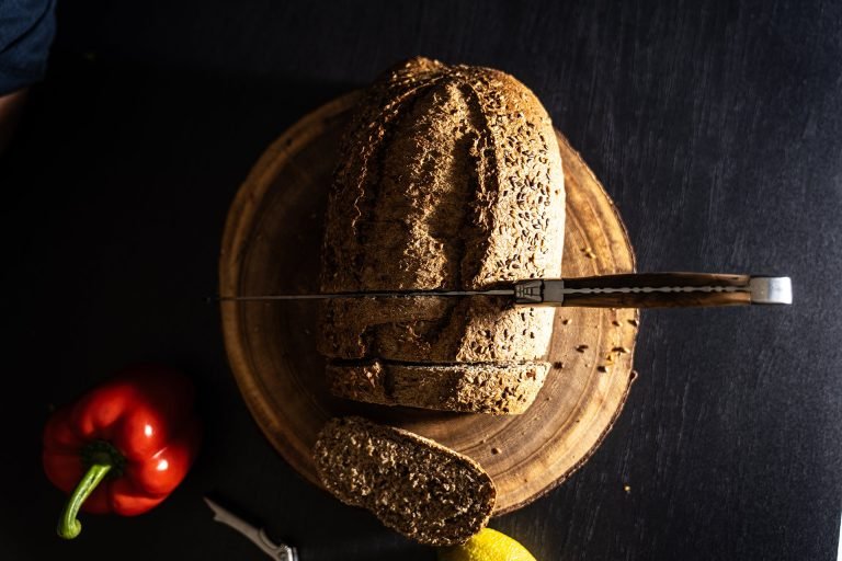 Laguiole bread knife lying across a sliced loaf of dark bread