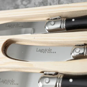 Close-up of the Laguiole Du Monde cheese knives with black handles in their wooden box